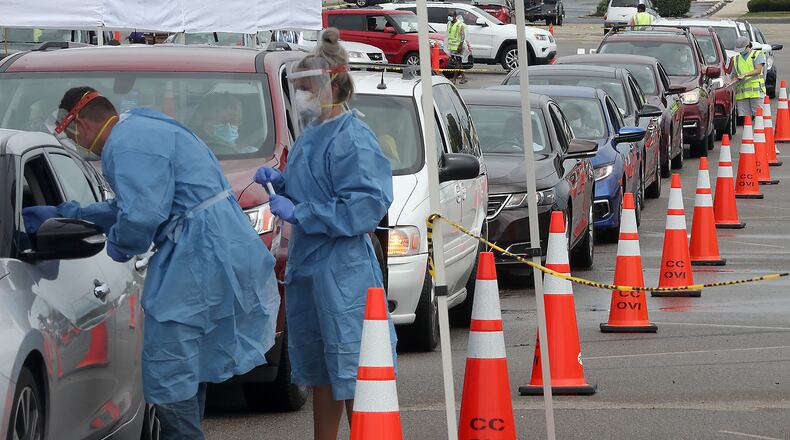 People wait in their cars for a free COVID-19 test at the Burnett Plaza parking lot. BILL LACKEY/STAFF