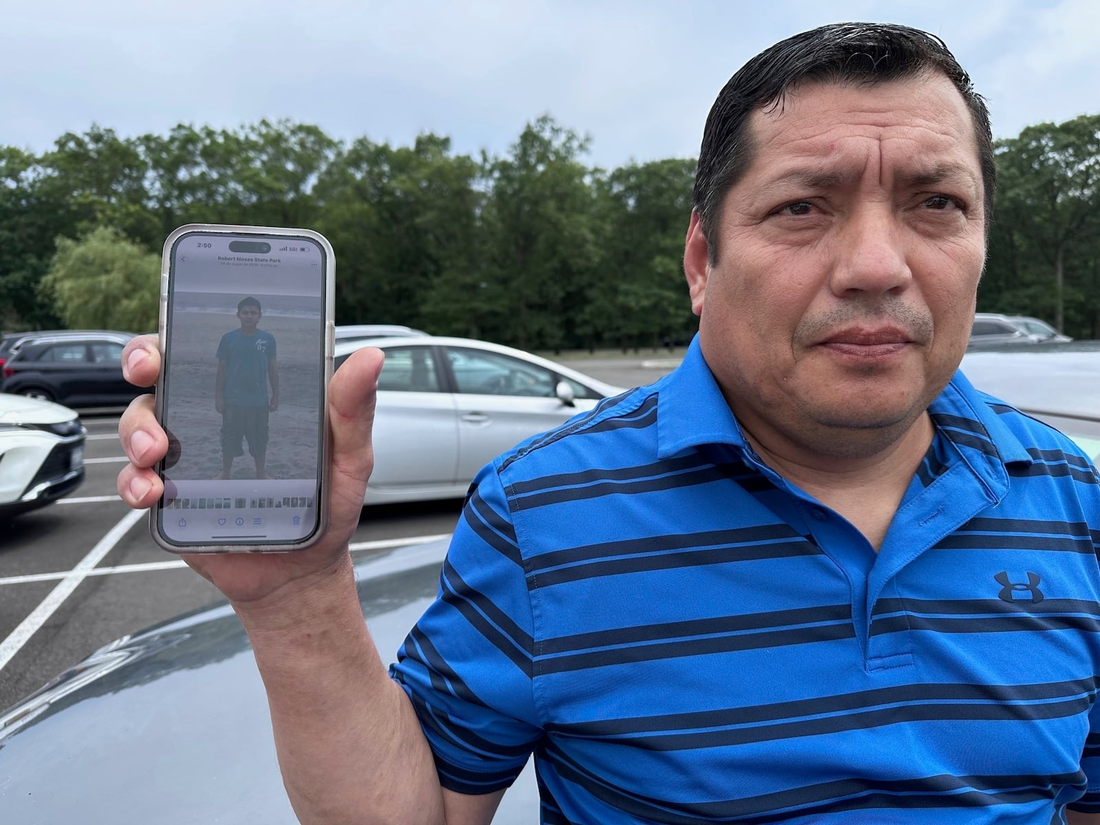 Santos Castillo stands outside federal court in Central Islip, N.Y., on Wednesday, July 2, 2025, holding up a photo on his phone of his son, Javier Castillo, who was slain by MS-13 gang members in 2016. (AP Photo/Philip Marcelo)
