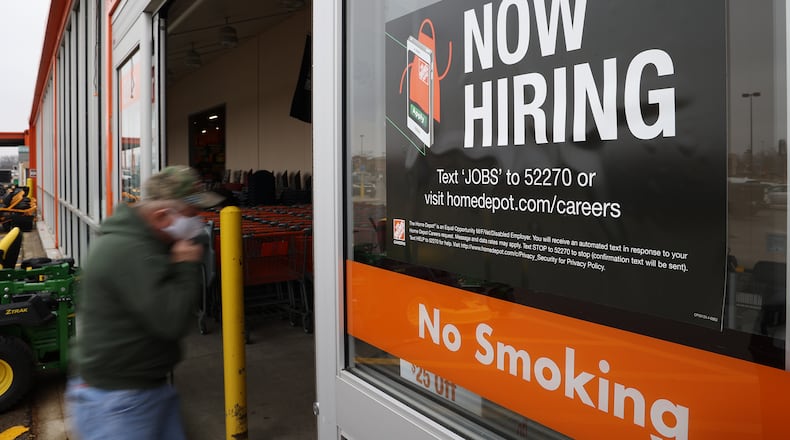 A customer walks past a "Now Hiring" sign at the entrance to Home Depot in Springfield earlier this year. BILL LACKEY/STAFF