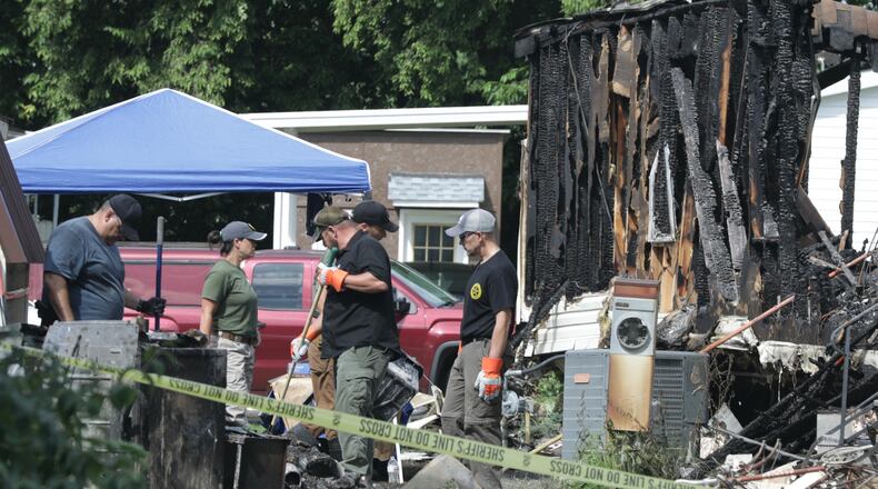 Investigators from BCI continue to sift through the remains of the burned out trailer at Harmony Estates Monday morning. BILL LACKEY/STAFF