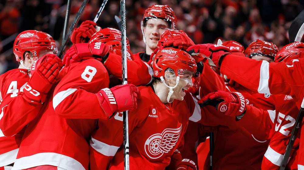 Detroit Red Wings right wing Patrick Kane, center, is surround by teammates after recording his 1,375th point to pass Mike Modano and break the NHL record for points by a player born in the United States, during the second period of an NHL hockey game Thursday, Jan. 29, 2026, in Detroit. (AP Photo/Duane Burleson)