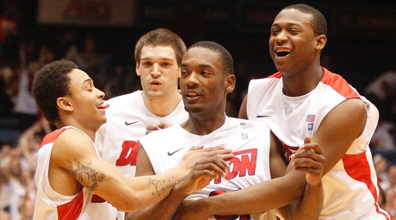 Dayton's Dyshawn Pierre, center, is congratulated by Kyle Davis, left, Alex Gavrilovic, back, and Kendall Pollard after hitting a 3-pointer at the buzzer to end the first half against Rhode Island on Wednesday, Feb. 12, 2014, at UD Arena. David Jablonski/Staff