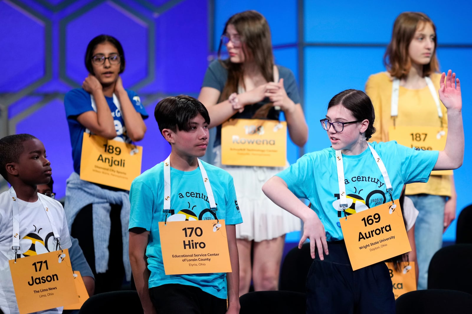 Aurora Ottilie Spisak, 14, of Dayton, Ohio, front right, stretches during a commercial break in the first preliminary round of the Scripps National Spelling Bee, Tuesday, May 27, 2025, in Oxon Hill, Md. (AP Photo/Julia Demaree Nikhinson)