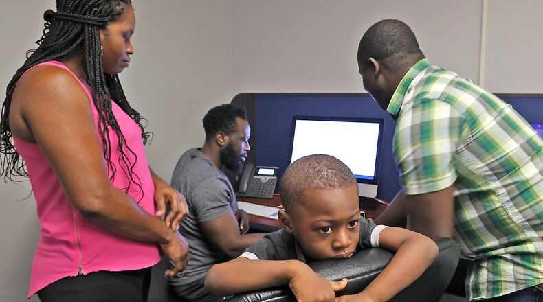 Kepler Jean Baptiste looks around the room as Malachi Thebaud, a bilingual assistant, right, helps his father, Jean Paul Jean Baptiste, and mother, Eveline Port Louis, register him for school in the Springfield City School District Tuesday, August 1, 2023. BILL LACKEY/STAFF