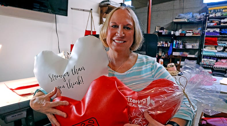 Lynette Evans holds some of her hand made heart pillows, which help people who have had open heart surgery, Wednesday, April 12, 2023 in her workshop. BILL LACKEY/STAFF