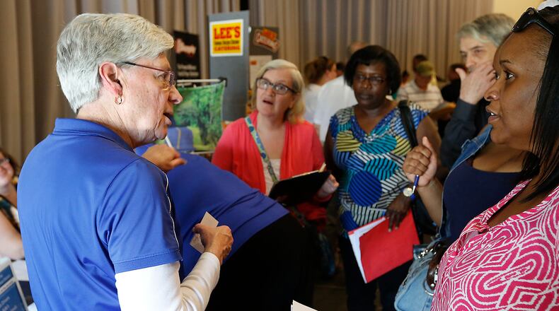Deb Dasher, from Springfield City Schools, is surrounded by people as she talks about job opportunities at the Chamber of Greater Springfield and OhioMeansJobs Clark County job fair . Bill Lackey/Staff