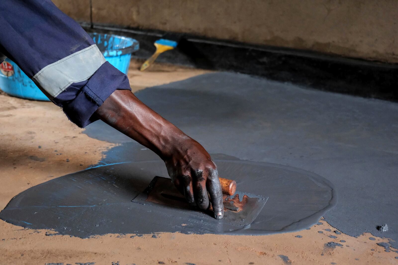 Alex Wanda, a construction officer at EarthEnable, installs paste on floors May 17, 2025, in Jinja, Uganda. (AP Photo/Hajarah Nalwadda)