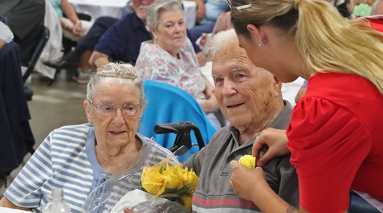 Rebekah Hardacre, the 2022 Clark County Fair Queen, pins a yellow rose on John Brown as he and his wife, Anna May, are crowned the King and Queen of the Golden Wedding Party Tuesday, July 26, 2022. The Browns have been married for 75 years. BILL LACKEY/STAFF