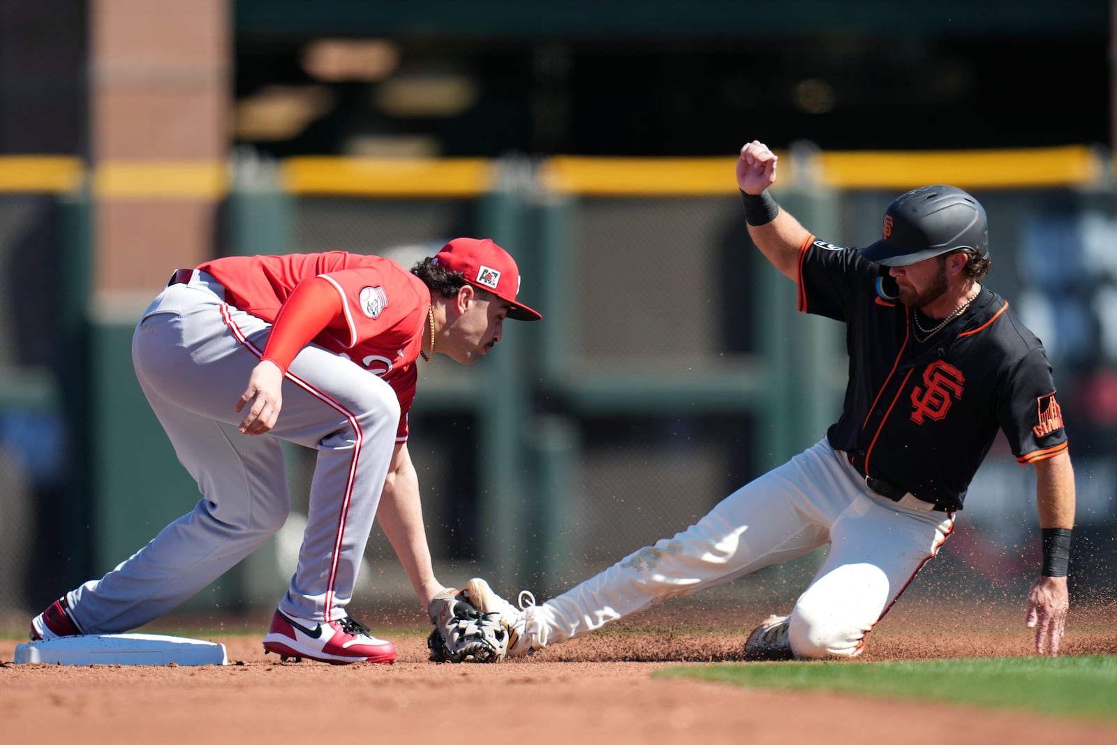 Cincinnati Reds second baseman Sal Stewart, left, tags out San Francisco Giants' Brett Wisely, right, as Wisely tries to steal second during the second inning of a spring training baseball game Sunday, Feb. 23, 2025, in Scottsdale, Ariz. (AP Photo/Ross D. Franklin)