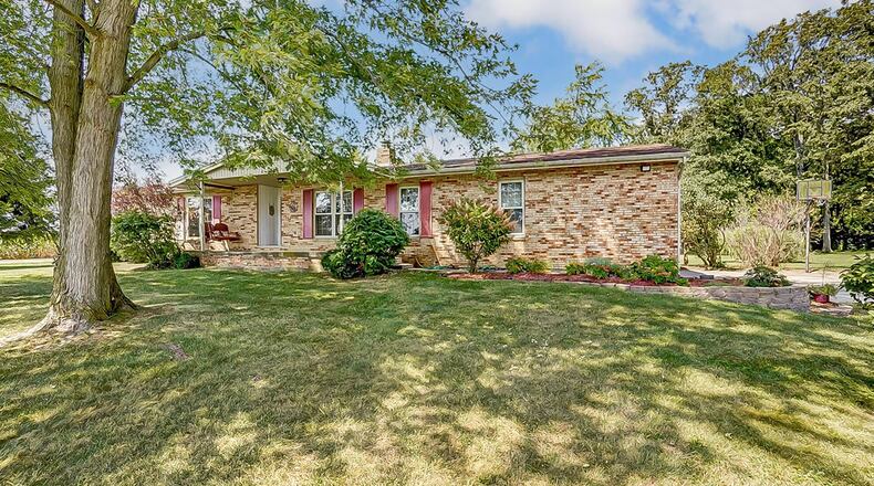 The front of the brick ranch style home has a covered front porch
