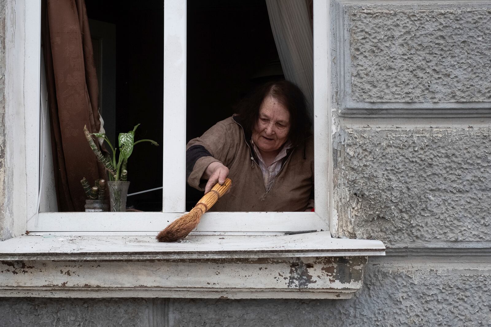 A woman cleans her window after a Russian missile strike on Sumy, Ukraine, Sunday April 13, 2025. (AP Photo/Volodymyr Hordiienko)