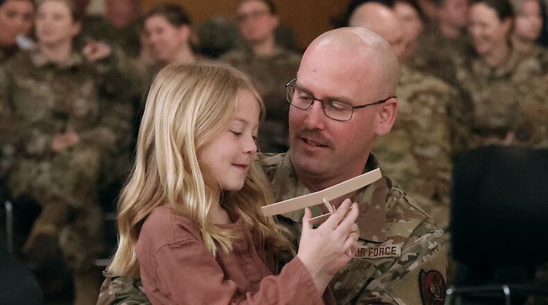 Master Sgt. Brock Cochran holds his daughter, Quinn, while her mother, Master Sgt. Amanda Cochran, participates in a Call to Duty Ceremony Sunday at the Springfield Air National Guard Base. Airman from the 178th Wing of the Air National Guard, including Master Sgt. Amanda Cochran, are deploying in support of the Air Force Central Command to provide tactical command and control capabilities.  BILL LACKEY/STAFF