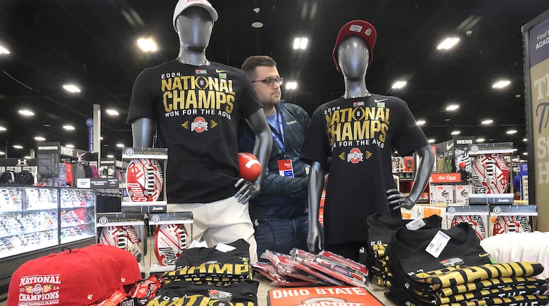Paul Wells, manager of Academy Sports in Springfield, sets up a display of Ohio State National Champions merchandise near the store's entrance Tuesday, Jan. 21, 2025. BILL LACKEY/STAFF
