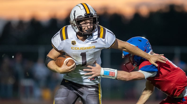 Kenton Ridge High School senior Heath Jones runs past Northwestern sophomore Ried Smith during their game on Friday night at Taylor Field in Springfield. The Cougars won 23-13. CONTRIBUTED PHOTO BY MICHAEL COOPER