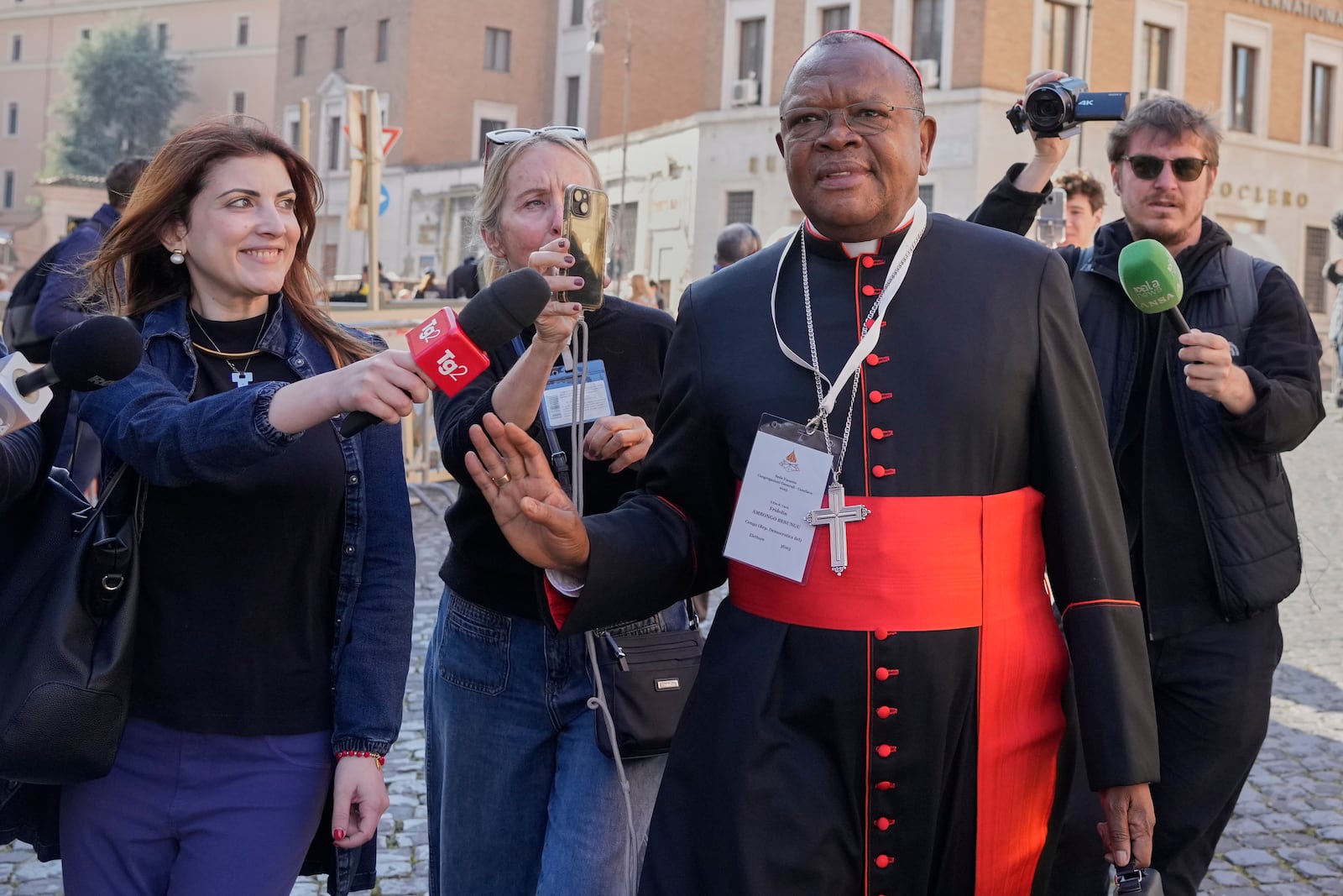 FILE - Cardinal Fridolin Ambongo Besungu is approached by reporters as he arrives for a college of cardinals' meeting, at the Vatican, Wednesday, April 30, 2025. (AP Photo/Gregorio Borgia, File)