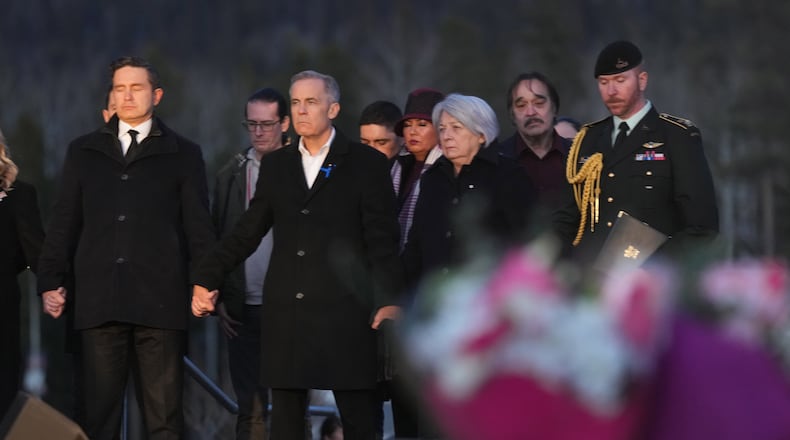 From left to right, Leader of the Official Opposition of Canada Pierre Poilievre, Prime Minister Mark Carney and Governor General of Canada, Mary Simon join hands while attending a vigil for the victims of a mass shooting, in Tumbler Ridge, B.C., Friday, Feb. 13, 2026. (Christinne Muschi/The Canadian Press via AP)