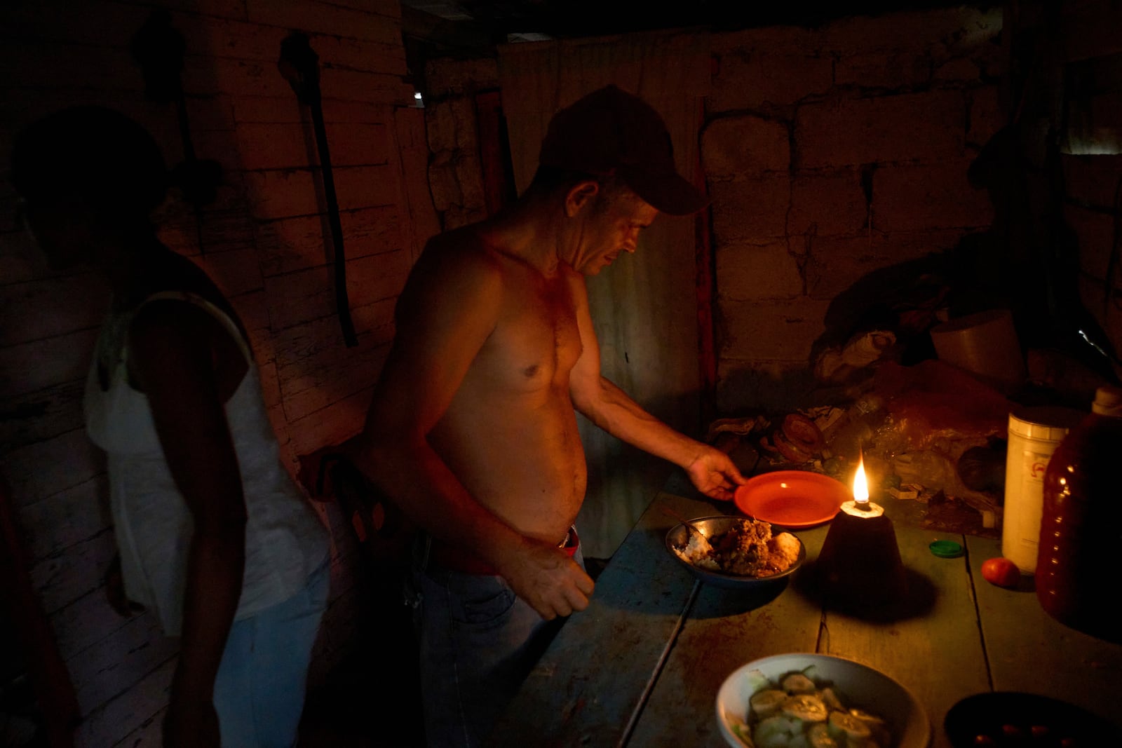 Edinector Vazquez prepares to eat dinner at his home lit by a gas lamp during a blackout in Minas, Havana province, Cuba, Monday, May 26, 2025. (AP Photo/Ramon Espinosa)