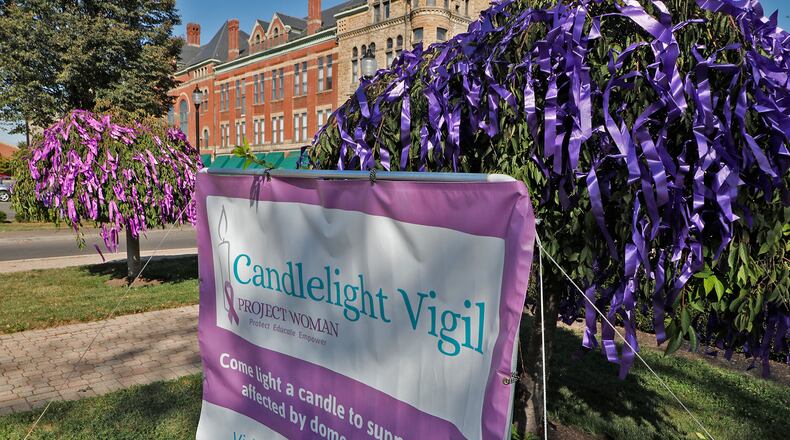 The trees and bushes around the Esplanade in downtown Springfield were decorated with purple ribbons for the Project Woman Candlelight Vigil for domestic violence last year. BILL LACKEY/STAFF