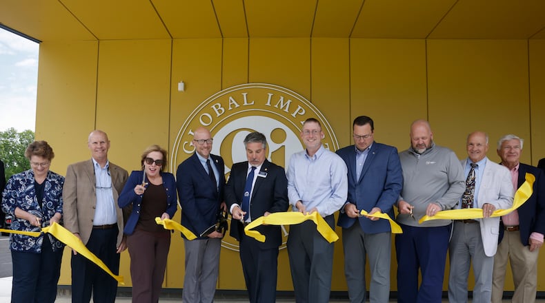 A group cuts a ribbon during a ceremony to celebrate the new upper academy of the Global Impact STEM Academy on Friday, May 23, 2025, at Clark State College. JOSEPH COOKE/STAFF
