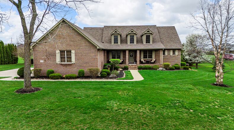 This brick two story features a main level primary suite, covered front porch with stone and brick accents and upper level dormers. The home sits on three acres.