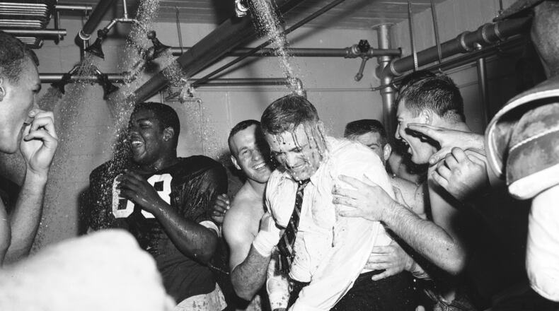 FILE - In this Nov. 16, 1957, file photo, Ohio State football coach Woody Hayes, center, gets a clothes-on dunking in the Ohio State dressing room shortly after Ohio State University won the Big Ten championship and clinched a Rose Bowl bid by defeating Iowa 17-13, in Columbus, Ohio. The Associated Press has been ranking the best teams in college football for the last 80 seasons. (AP Photo/File)