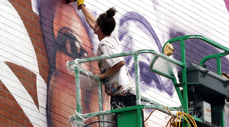 Muralist Gaia, from New York City, works on the mural of Springfield civil rights advocate Hattie Moseley on Thursday, Oct. 6, 2022 on the side of the WesBanco building in downtown Springfield. BILL LACKEY/STAFF