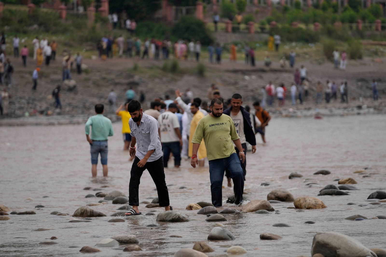 People cross the Chenab River after the flow of water was halted from a dam, at Akhnoor, on the outskirts of Jammu, India, Monday, May 5, 2025. (AP Photo/Channi Anand)