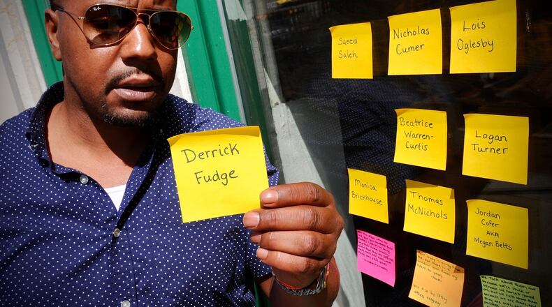Dion Green’s father Derrick Fudge was one of the victim’s of the Oregon Street shooting two years ago holds up a post-it note with his father’s name that someone had left with the other names for victims on a window on Fifth St., Tuesday, August 2, 2021. MARSHALL GORBY\STAFF