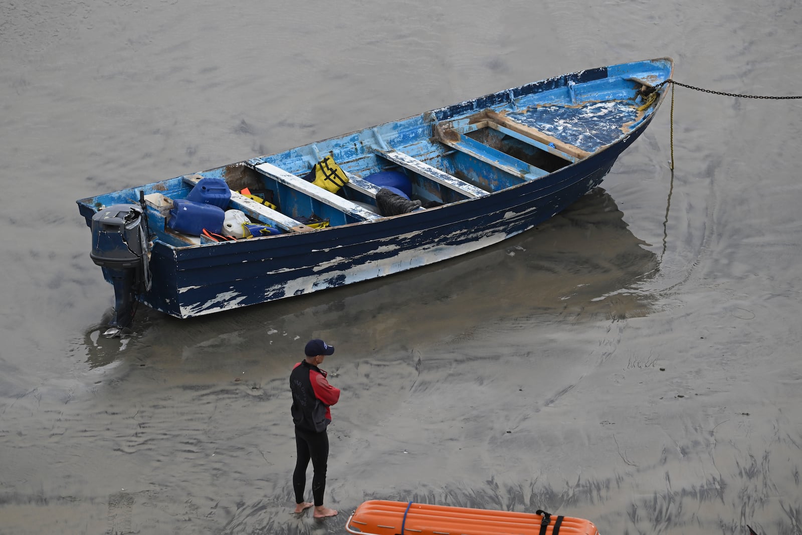 Del Mar lifeguards looks over a capsized boat on the beach Monday, May 5, 2025, in at Torrey Pines State beach in San Diego, Calif. (AP Photo/Denis Poroy)