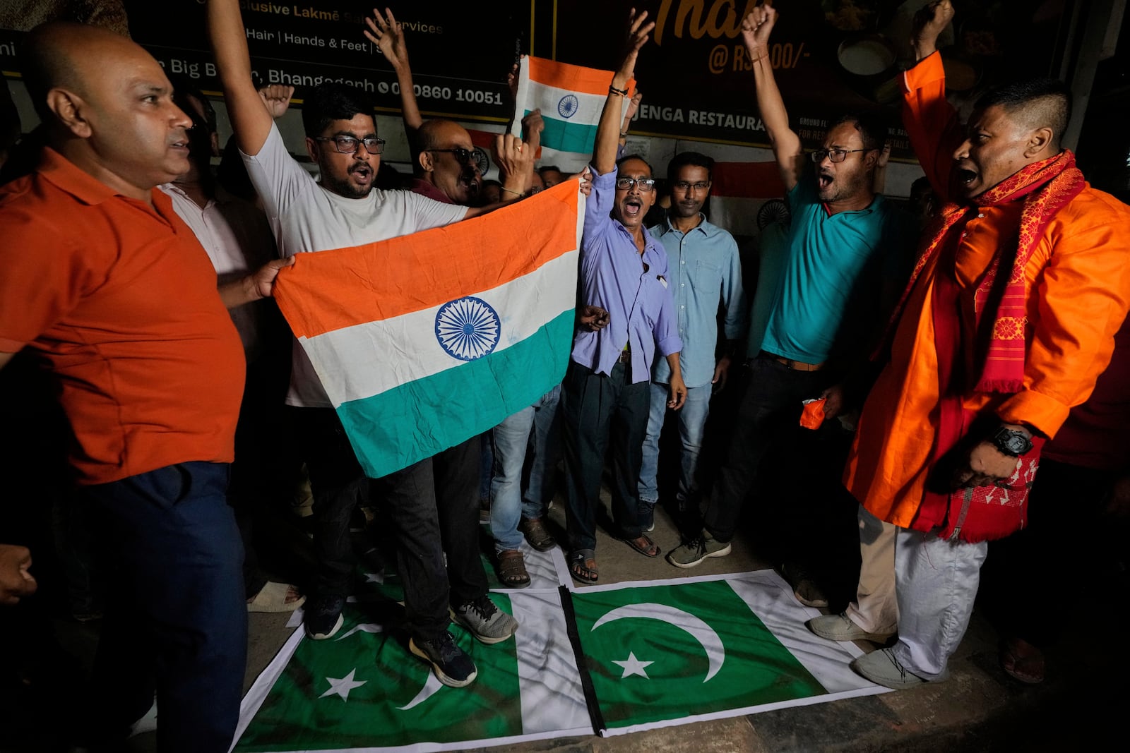 People stand over Pakistani flags and holding Indian national flags chant slogans in favor of the Indian Army as they celebrate the success of 'Operation Sindoor', in Guwahati, India, Thursday, May 8, 2025. (AP Photo/Anupam Nath)