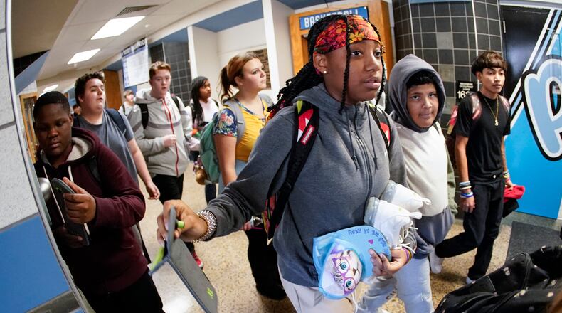 Students at the Washington Junior High School leaving classes for the day use the unlocking mechanism to open the bags their cell phone were sealed in during the school day, Oct. 27, 2022, in Washington, Pa. Citing mental health, behavior and engagement as the impetus, many educators are updating cellphone policies, with a number turning to magnetically sealing pouches. (AP Photo/Keith Srakocic)