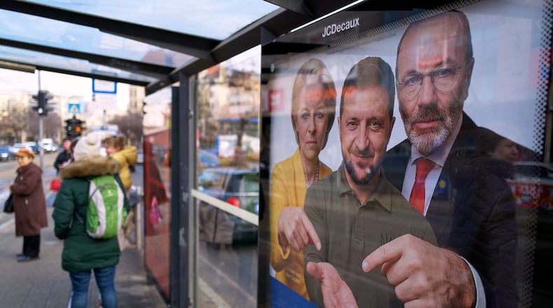 A billboard showing an AI-generated image of Ukrainian President Volodymyr Zelenskyy, center, flanked by European officials is displayed at a bus stop in Budapest, Hungary, Monday, Feb. 23, 2026. (AP Photo/Bela Szandelszky)