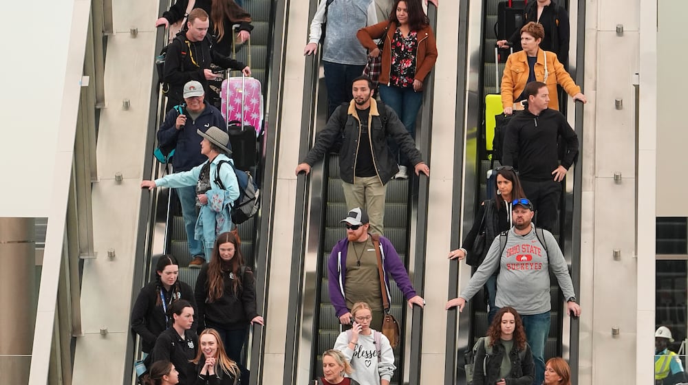 Travellers head down an escalator after clearing through a security checkpoint in Denver International Airport Friday, Nov. 7, 2025, in Denver. (AP Photo/David Zalubowski)