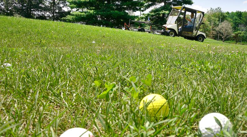 The tall grass makes it hard for a grounds keeper to pick up the balls on the driving range at Locust Hills Golf Course Thursday. Bill Lackey/Staff