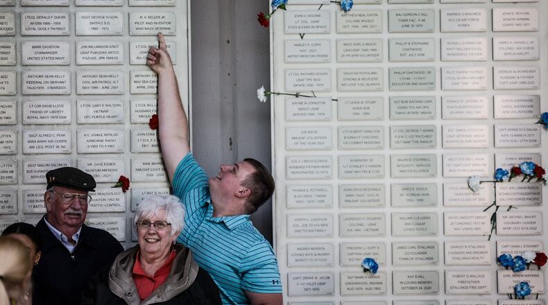 Ash Williams from New Madison points up at his Great Grandfathers, WWII veteran Robert Schlotterbeck's plack.
The Air Force Museum held its first Honor Plate Ceremony since the pandemic three years ago. A total of 475 new names were added to the wall. After the ceremony, family and friends hung flowers near their loved one's plates. JIM NOELKER/STAFF