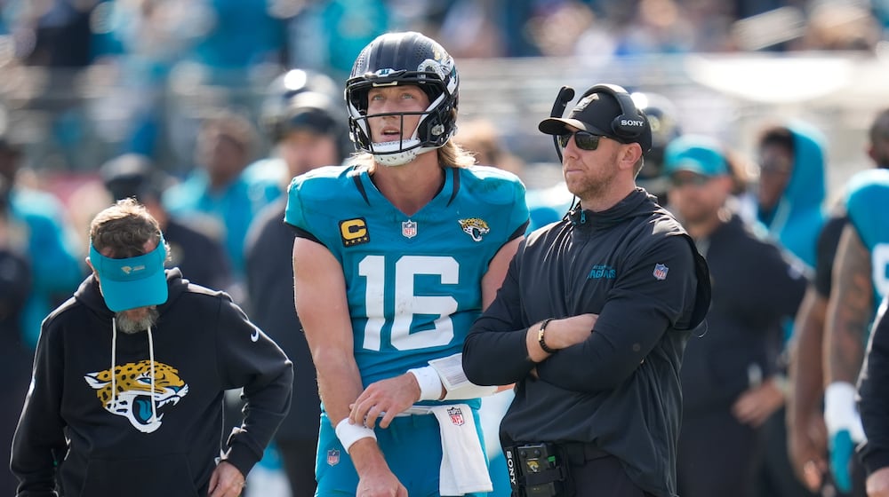 Jacksonville Jaguars quarterback Trevor Lawrence (16) stands next to head coach Liam Coen during the first half of an NFL wild-card playoff football game against the Buffalo Bills Sunday, Jan. 11, 2026, in Jacksonville, Fla. (AP Photo/John Raoux)
