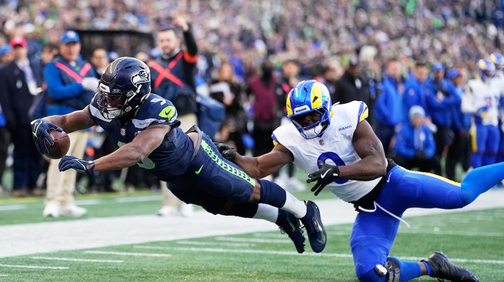 Seattle Seahawks running back Kenneth Walker III (9) scores a touchdown past Los Angeles Rams linebacker Byron Young (0) during the first half of the NFC Championship NFL football game Sunday, Jan. 25, 2026, in Seattle. (AP Photo/Stephen Brashear)
