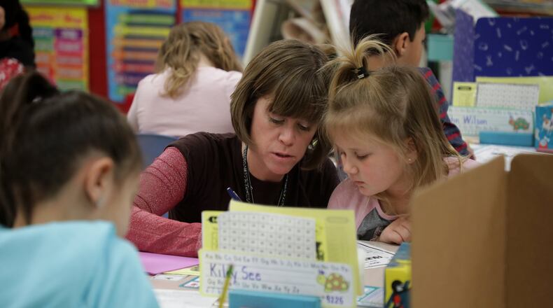Second grade teacher Heidi Kottmyer helps students in her class at Donnelsville Elementary last year. BILL LACKEY/STAFF