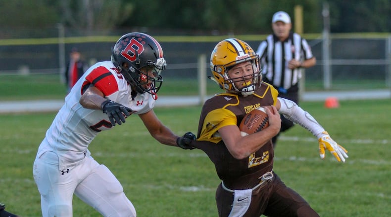 Kenton Ridge High School quarterback Dylan Lemen runs away from Bellefontaine’s Tank Pence last season. Michael Cooper/CONTRIBUTED