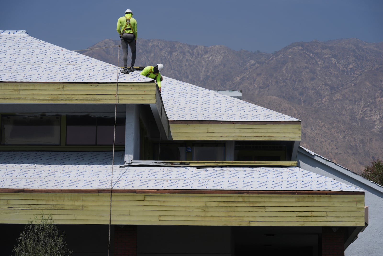 Construction workers install new roofing in Altadena, Calif., on Tuesday, April 22, 2025. (AP Photo/Damian Dovarganes)