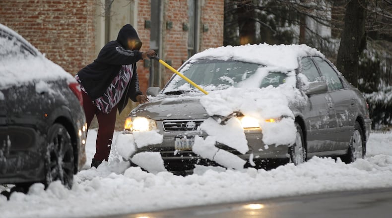 A Xenia resident clears heavy wet snow from her car on East Second Street on Wednesday morning after an overnight storm brought snow and freezing rain to the area. TY GREENLEES / STAFF