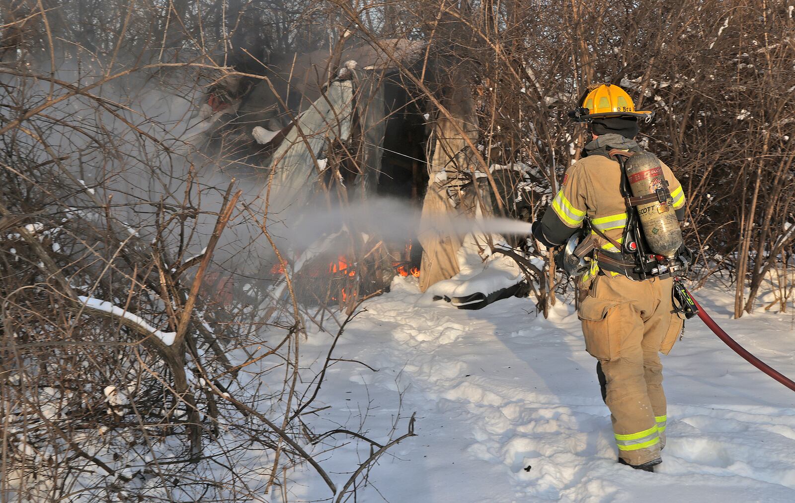 A Member of the Springfield Fire & Rescue Division extinguishes a fire at a homeless encampment along East High Street Thursday, Jan. 9, 2025. The residents of the encampment were not present when the fire department arrived. BILL LACKEY/STAFF