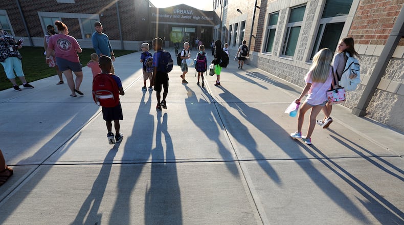 Urbana Elementary School students cast long shadows on the walkway as they walk into school for the first day Monday morning. BILL LACKEY/STAFF