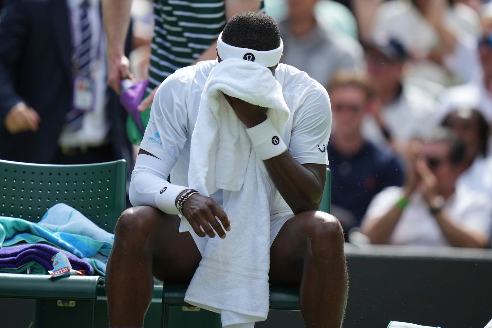 Frances Tiafoe of the U.S. wipes his face during a change of ends break as he plays Cameron Norrie of Britain during their second round men's singles match at the Wimbledon Tennis Championships in London, Wednesday, July 2, 2025. (AP Photo/Alastair Grant)