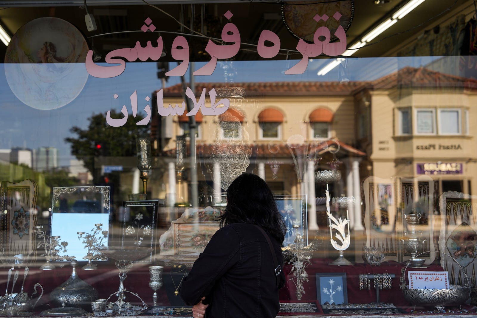 A woman looks into the window of a store selling Persian souvenirs in the "Tehrangeles" neighborhood of Los Angeles Tuesday, June 24, 2025. (AP Photo/Jae C. Hong)