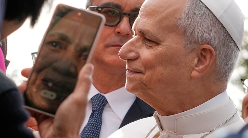 The head of Vatican Security, Gianluca Gauzzi Broccoletti, center, follows Pope Leo XIV as he visits the parish complex of Santa Maria della Presentazione on the outskirts of Rome, Sunday, March 8, 2026. (AP Photo/Gregorio Borgia)