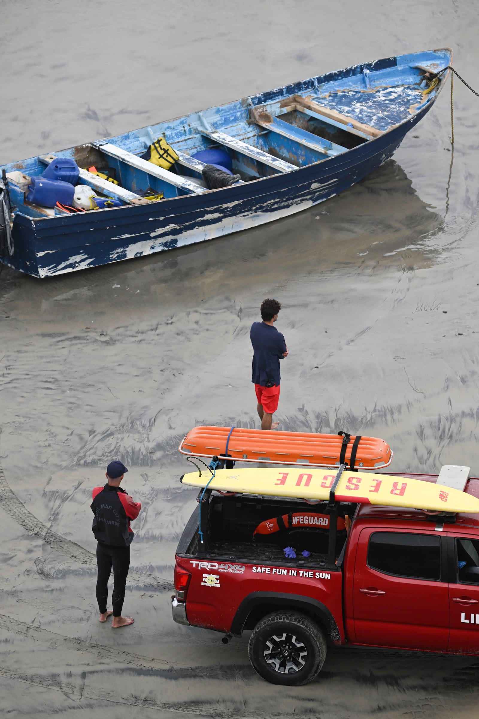 Del Mar lifeguards looks over a capsized boat on the beach Monday, May. 5, 2025, in at Torrey Pines State beach in San Diego, Calif. (AP Photo/Denis Poroy)