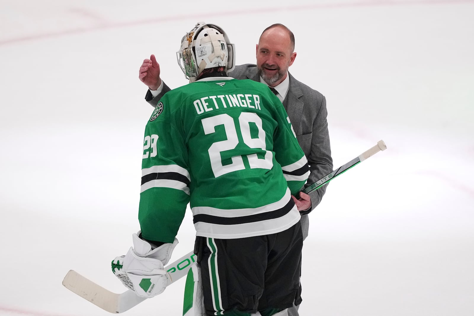 Dallas Stars goaltender Jake Oettinger (29) and head coach Pete DeBoer, rear, celebrate the teams 4-2 win against the Colorado Avalanche in Game 7 of a first-round NHL hockey playoff series Saturday, May 3, 2025, in Dallas. (AP Photo/Julio Cortez)