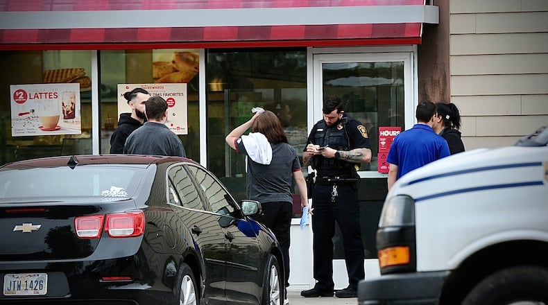 A member of the Springfield Police Division interviews employees of the Tim Horton’s on East Main Street on Monday morning, May 15, 2023, after a customer reportedly assaulted one of the employees. MARSHALL GORBY \STAFF