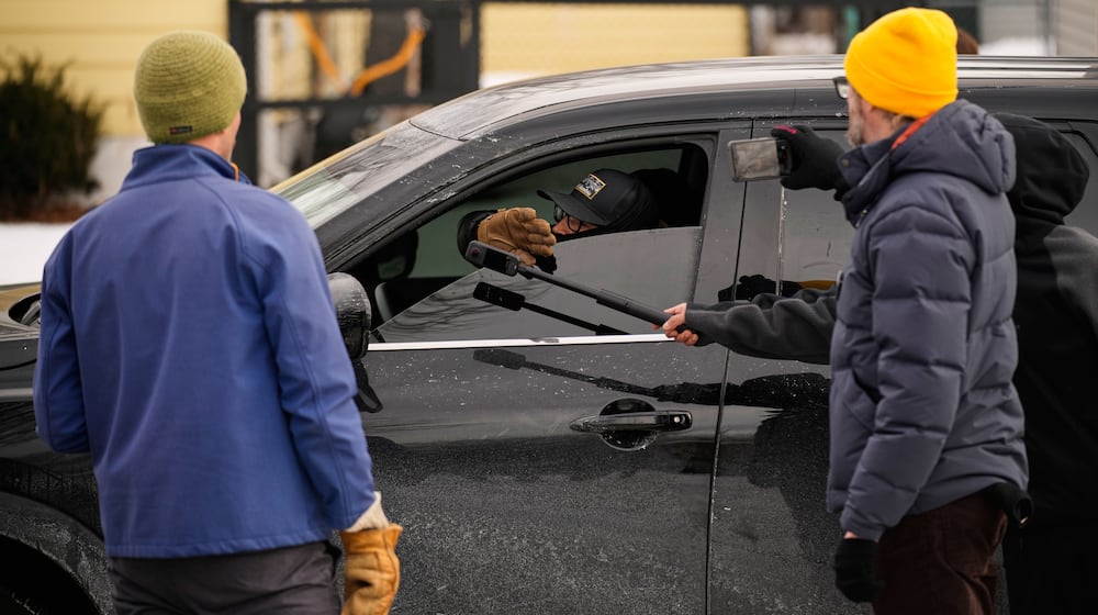 Bystanders film a federal immigration officer in their car Sunday, Jan. 11, 2026, in Minneapolis. (AP Photo/John Locher)